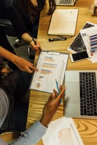 Team members analyzing business charts and reports in an office setting around a wooden table.