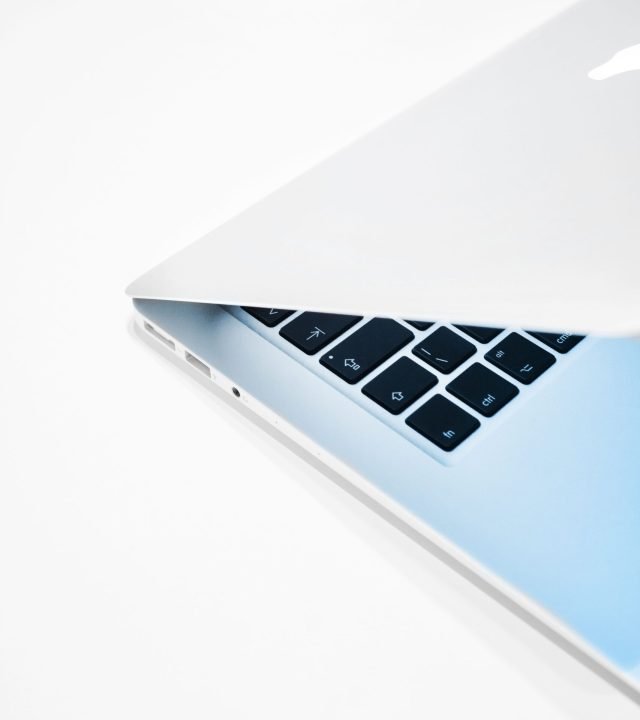 Close-up of a sleek laptop slightly opened on a crisp white background.